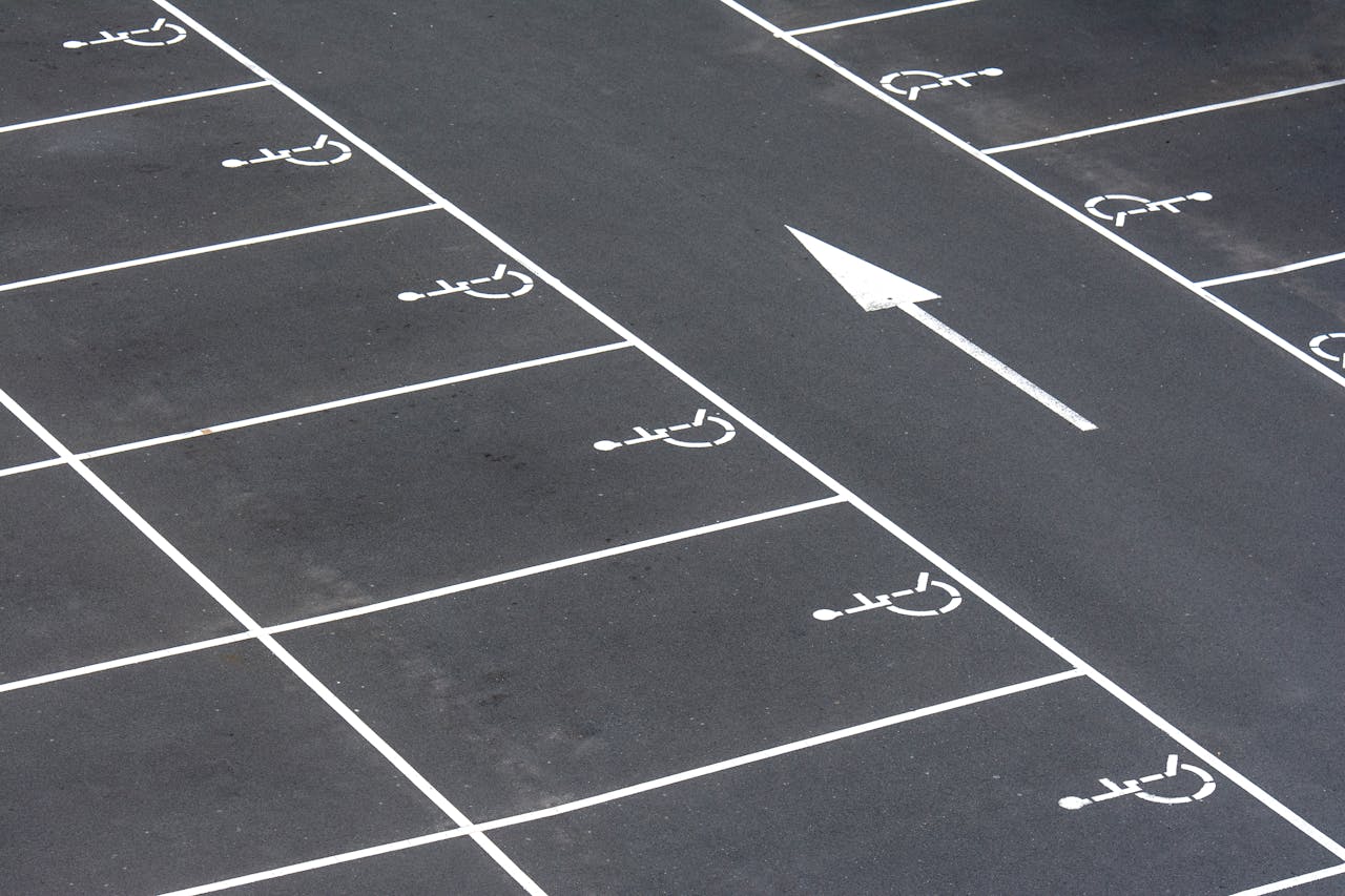 An aerial view of an empty parking lot with handicap spaces and directional arrow.